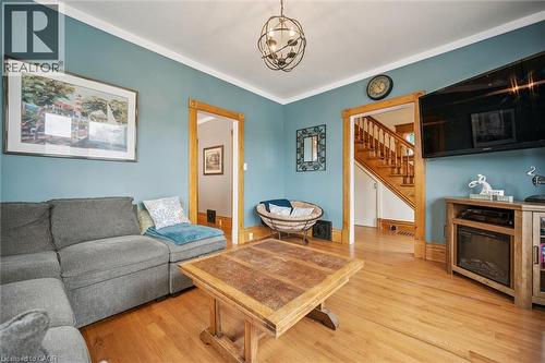 This inviting living space features hardwood floors, a decorative light fixture, and a wooden staircase - 155 Lancaster Street E, Kitchener, ON - Indoor Photo Showing Living Room