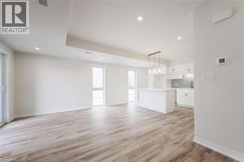 The open concept living area features light wood-style flooring, white walls, recessed lighting, and large windows providing ample natural light - 686 Benninger Drive, Kitchener, ON - Indoor