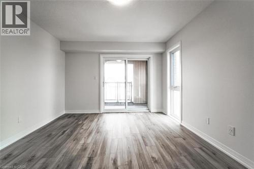 Room featuring light-colored walls, wood-look flooring, and a sliding glass door leading to a balcony with metal railings - 686 Benninger Drive, Kitchener, ON - Indoor Photo Showing Other Room