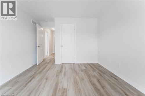 This room features light-colored laminate flooring, white walls, and white baseboards - 686 Benninger Drive, Kitchener, ON - Indoor Photo Showing Other Room