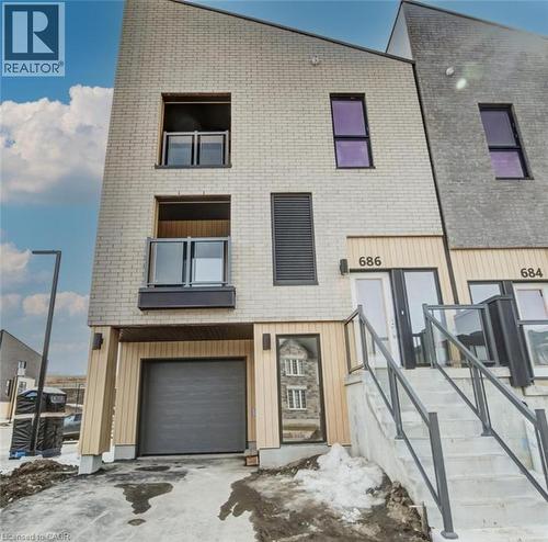 The property features a modern facade with light-colored brick and wood-paneled accents, a garage, and balconies with glass railings - 686 Benninger Drive, Kitchener, ON - Outdoor
