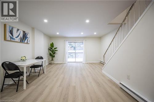 The property features light-toned flooring, a staircase with white railings, and a sliding glass door providing natural light - 212 Westcourt Place, Waterloo, ON - Indoor Photo Showing Other Room