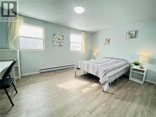 This room features light-colored plank flooring, light blue walls, and two windows with curtains - 212 Westcourt Place, Waterloo, ON - Indoor Photo Showing Bedroom