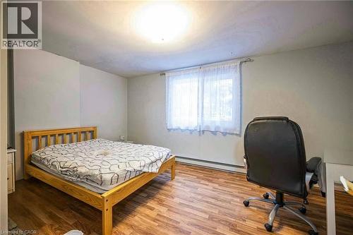 This room features wood-look flooring, light-colored walls, and a window with white curtains - 212 Westcourt Place, Waterloo, ON - Indoor Photo Showing Other Room