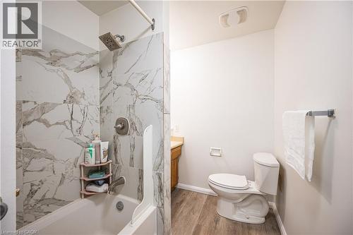 This bathroom features a bathtub and shower combination with white and gray marbled tile surround, a built-in shower caddy, and a shower head with a rain shower feature - 212 Westcourt Place, Waterloo, ON - Indoor Photo Showing Bathroom
