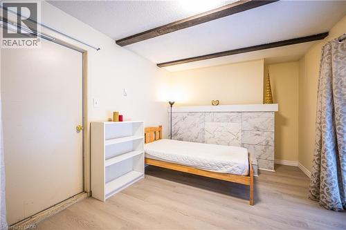This room features a white ceiling with exposed wooden beams, light-colored flooring, and a decorative wall with a marbled tile pattern - 212 Westcourt Place, Waterloo, ON - Indoor Photo Showing Bedroom