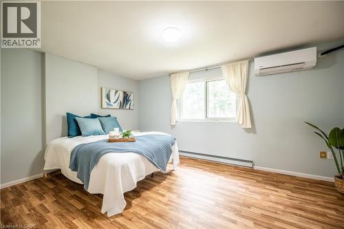 Room featuring wood-finish flooring, a window with natural light, and a wall-mounted mini-split system - 212 Westcourt Place, Waterloo, ON 