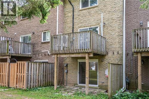 Rear exterior featuring a ground-level patio, wood privacy fencing, and an upper-level wood deck - 212 Westcourt Place, Waterloo, ON 