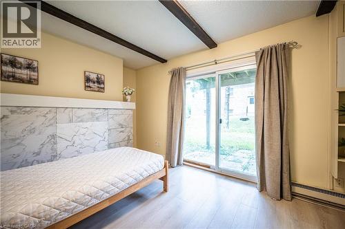 Interior space featuring exposed ceiling beams, light wood-finish flooring, and a sliding glass door providing direct outdoor access - 212 Westcourt Place, Waterloo, ON - Indoor Photo Showing Bedroom
