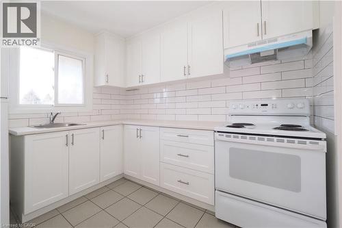 The kitchen features white cabinetry, a subway tile backsplash, and a white electric range - 24 Austin Drive, Waterloo, ON - Indoor Photo Showing Kitchen