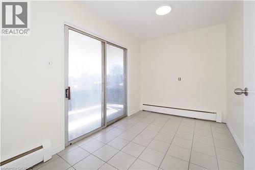 This room features light-colored tiled flooring, a sliding glass door, and white walls - 24 Austin Drive, Waterloo, ON - Indoor Photo Showing Other Room