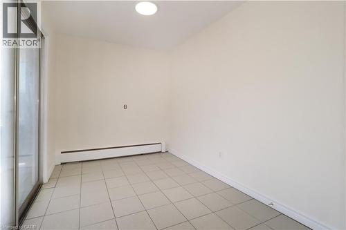 This bright space features tile flooring, baseboard heating, a ceiling light fixture, and a sliding glass door - 24 Austin Drive, Waterloo, ON - Indoor Photo Showing Other Room
