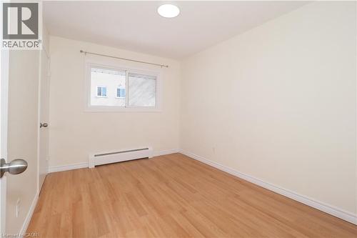 Bright room featuring light-toned hardwood flooring, a window with a curtain rod, and a baseboard heater - 24 Austin Drive, Waterloo, ON - Indoor Photo Showing Other Room