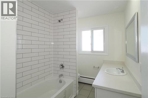 Bathroom featuring a bathtub with subway tile surround, a vanity with an integrated sink, and a framed mirror - 24 Austin Drive, Waterloo, ON - Indoor Photo Showing Bathroom