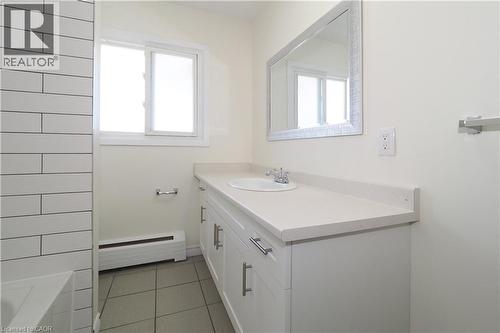 This bathroom features a vanity with a light-colored countertop and a rectangular mirror with a textured frame - 24 Austin Drive, Waterloo, ON - Indoor Photo Showing Bathroom