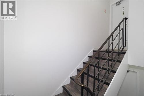 Stairway featuring wood-look treads, white risers, and a dark-toned metal handrail - 24 Austin Drive, Waterloo, ON - Indoor Photo Showing Other Room