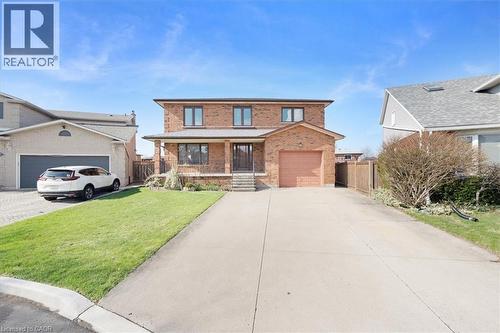 The property features a brick exterior, an integrated garage, and a concrete driveway - 18 Marcel Place, Hamilton, ON - Outdoor With Deck Patio Veranda