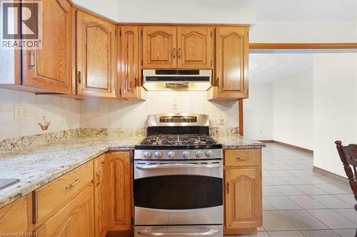The kitchen features light wood cabinetry, stone countertops, and a stainless steel range with an overhead vent - 18 Marcel Place, Hamilton, ON - Indoor Photo Showing Kitchen