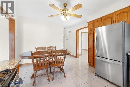 The kitchen features ample wood cabinetry, a stainless steel refrigerator, and tiled flooring - 18 Marcel Place, Hamilton, ON - Indoor Photo Showing Dining Room