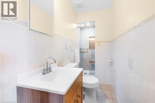 Bathroom featuring a vanity with a white countertop and a chrome faucet, a toilet, and a tiled shower with a built-in bench - 18 Marcel Place, Hamilton, ON - Indoor Photo Showing Bathroom