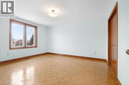 This room features parquet flooring, light blue walls, and a window with a wood frame - 18 Marcel Place, Hamilton, ON - Indoor Photo Showing Other Room