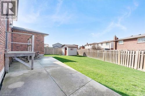 The property features a concrete patio area, a wooden deck, and a fenced yard with a lawn - 18 Marcel Place, Hamilton, ON - Outdoor