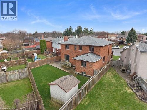 The property features a brick exterior, a well-maintained lawn, a wooden fence enclosing the yard, and a shed - 18 Marcel Place, Hamilton, ON - Outdoor