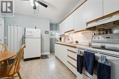 The kitchen features white cabinetry with wood trim, a white electric range, a white refrigerator, and a ceiling fan - 28 Davidson Street, Cambridge, ON - Indoor Photo Showing Kitchen