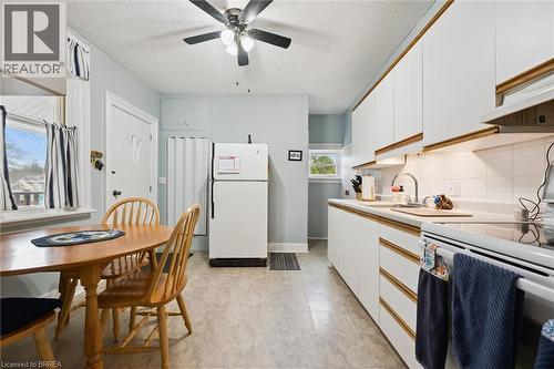 The property features a kitchen with white cabinetry, a ceiling fan, and a window providing natural light - 28 Davidson Street, Cambridge, ON - Indoor Photo Showing Kitchen