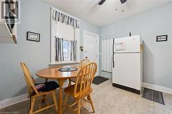 The kitchen features light-colored walls, a window with curtains, and a ceiling fan - 