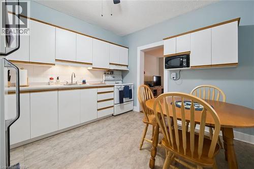 The kitchen features white cabinetry with wood trim, a white tile backsplash, and a white refrigerator - 28 Davidson Street, Cambridge, ON - Indoor