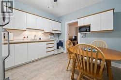 The kitchen features white cabinetry with wood trim, a white tile backsplash, and a white refrigerator - 