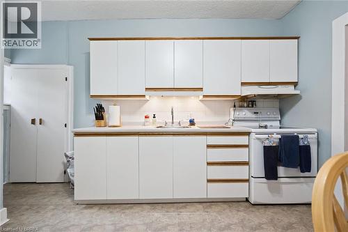 The kitchen features white cabinetry with wood trim, a white countertop, and a white oven with a range hood - 28 Davidson Street, Cambridge, ON - Indoor Photo Showing Kitchen