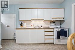 The kitchen features white cabinetry with wood trim, a white countertop, and a white oven with a range hood - 