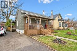 The property features a front porch with wooden railings and steps, a paved driveway, and a well-maintained lawn - 
