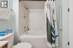 Bathroom featuring a bathtub with tiled surround, a shower head, and a toilet - 