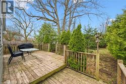 Expansive wooden deck with railing, offering views of mature trees and landscaping - 