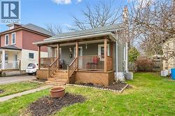The property features a charming front porch with wooden railings and steps, set on a grassy yard with a concrete pathway leading to the entrance - 