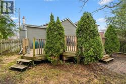 The property features a wood deck with railings and steps, surrounded by mature evergreen trees - 