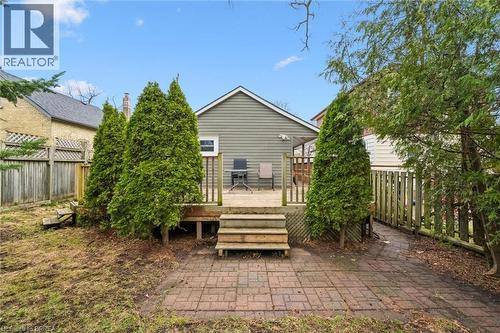 The property features a rear deck with wooden steps, surrounded by mature evergreen trees - 28 Davidson Street, Cambridge, ON - Outdoor