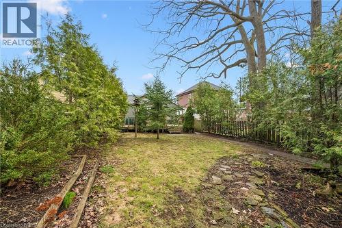 The property features a spacious yard with a lawn, mature trees, and a wooden fence - 28 Davidson Street, Cambridge, ON - Outdoor