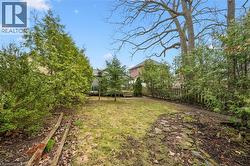 The property features a spacious yard with a lawn, mature trees, and a wooden fence - 