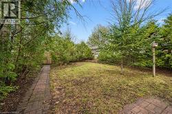 The expansive yard features a lawn, mature trees, and a brick pathway leading to a wooden fence - 