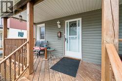The property features a front porch with natural wood decking and railings, complemented by green horizontal siding - 