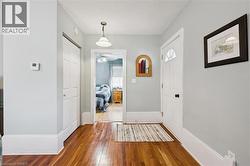 Entryway featuring hardwood floors, a white front door with an arched window insert, and a closet with bifold doors - 