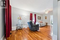 This living space features hardwood floors, light-colored walls, and a ceiling fan - 