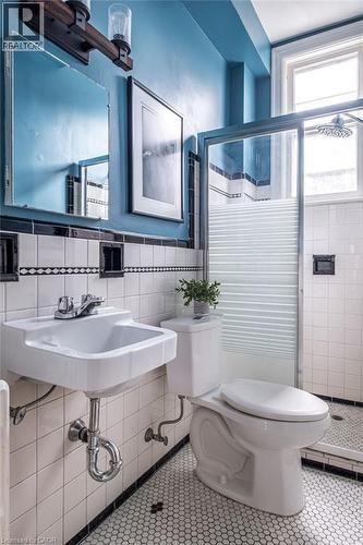 A bathroom featuring white subway tile walls with black trim, a hexagonal tile floor, and a walk-in shower with a glass enclosure - 36 Eastbourne Avenue, Hamilton, ON - Indoor Photo Showing Bathroom