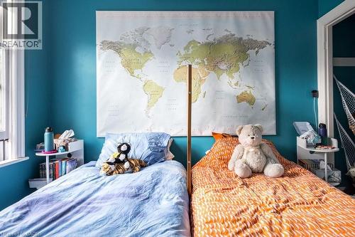 Bedroom featuring a window with white trim, two beds with different colored bedding, and walls painted in a vibrant blue hue - 36 Eastbourne Avenue, Hamilton, ON - Indoor Photo Showing Bedroom