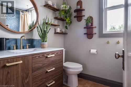Bathroom featuring a vanity with a white countertop, a mirror with a wooden frame, and a tile backsplash - 36 Eastbourne Avenue, Hamilton, ON - Indoor Photo Showing Bathroom