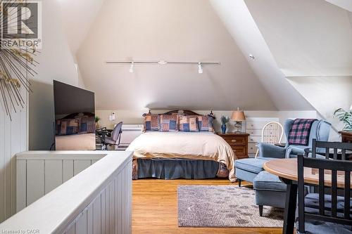 This property features vaulted ceilings, hardwood floors, track lighting, and a partial wall with vertical wood paneling - 36 Eastbourne Avenue, Hamilton, ON - Indoor Photo Showing Bedroom